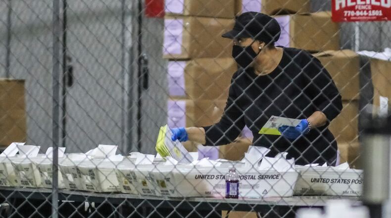 A Fulton County election worker opens and sorts absentee ballots at the Georgia World Congress Center in downtown Atlanta during this month's U.S. Senate runoffs. (John Spink / John.Spink@ajc.com)