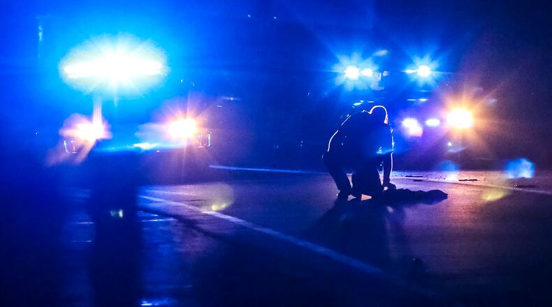 A DeKalb County police officer examines clothing left on the highway at the scene. A naked man sitting in the middle of I-85 North in DeKalb County was hit and killed in Sept. 2017. JOHN SPINK/JSPINK@AJC.COM