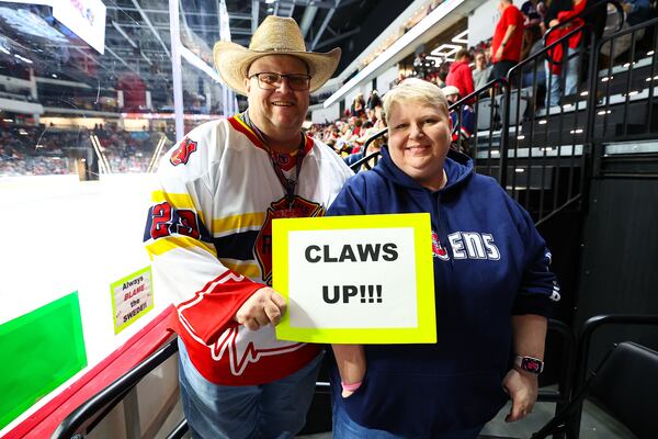 Athens Rock Lobsters fans Larry Wise, left, and Tia Wise, right, tape signs to the glass in front of their seats. The messages range from inside jokes with Rock Lobsters players to simple one-liners like “Your Mom” aimed at opponents. (Colin Hubbard for the AJC)