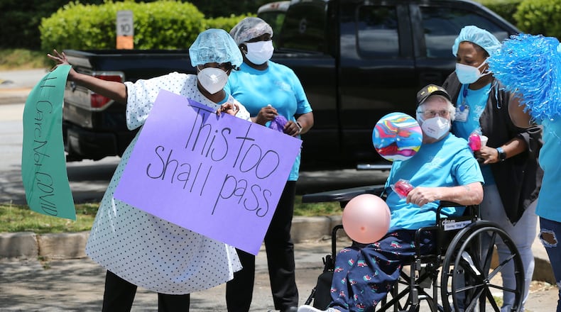 Workers celebrate during a family and community parade for residents and staff who have survived COVID-19 at Westbury Medical Care & Rehabilitation in Jackson, on May 13, 2020. Family members and supporters decorated vehicles with signs and posters and for many it was the first opportunity to see loved ones in months. Curtis Compton ccompton@ajc.com