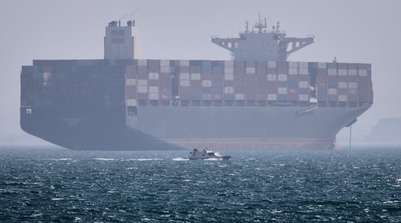A container ship sits at anchor as a small motorboat passes in the foreground in the Strait of Hormuz off Bandar Abbas, Iran, Saturday, May 2, 2026. (Amirhosein Khorgooi/ISNA via AP)