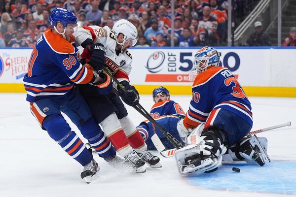 Florida Panthers' Brad Marchand (63) scores against Edmonton Oilers goalie Calvin Pickard (30) as OIlers' Corey Perry (90) defends and Oilers' Jake Walman, second from left, watches during the third period in Game 5 of the NHL hockey Stanley Cup Final in Edmonton, Alberta, Saturday, June 14, 2025. (Darryl Dyck/The Canadian Press via AP)