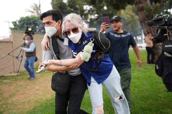 A man helps an injured woman during a protest in the Paramount section of Los Angeles, Saturday, June 7, 2025, after federal immigration authorities conducted operations. (AP Photo/Eric Thayer)