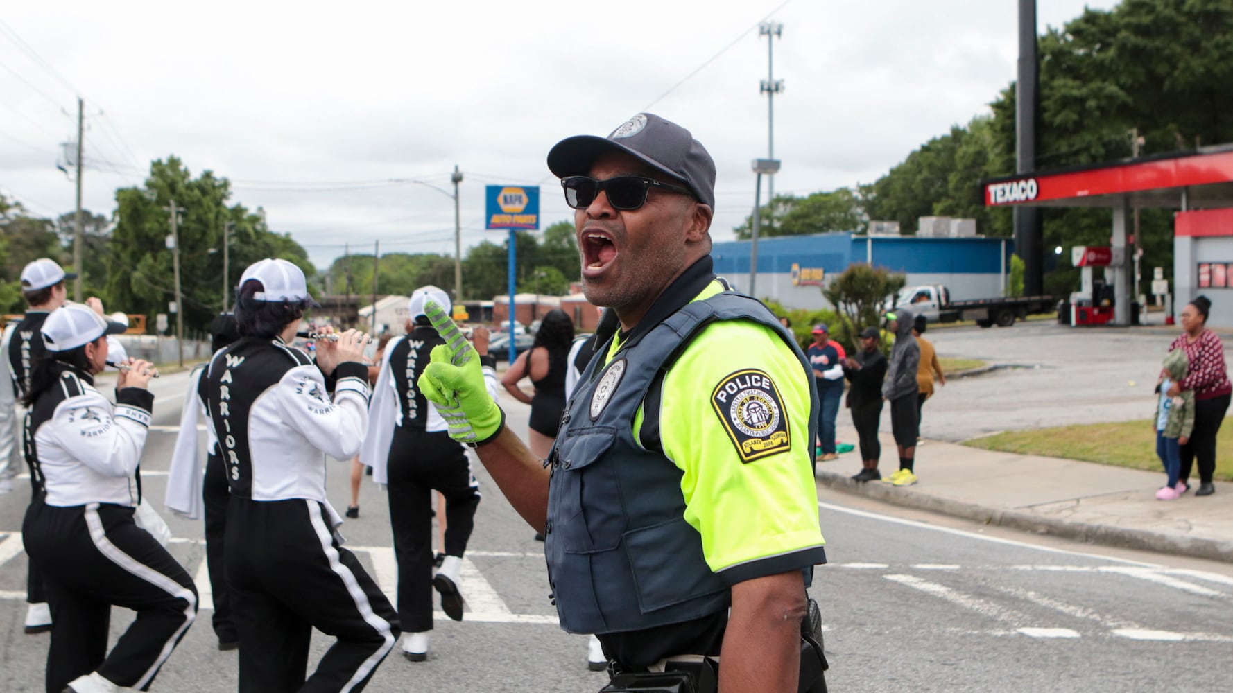 A police officer directs traffic and cheers on students marching in the Atlanta Public School parade on Saturday, April 22, 2023. The parade celebrated the 150th anniversary of Atlanta Public Schools and featured students, teachers and other members of the APS community. CHRISTINA MATACOTTA FOR THE ATLANTA JOURNAL-CONSTITUTION