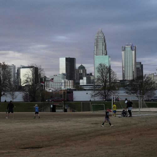 FILE - Children walk through a sports field in Independence Park under the skyline of Charlotte, N.C., on March 20, 2025. (AP Photo/Mary Conlon, File)