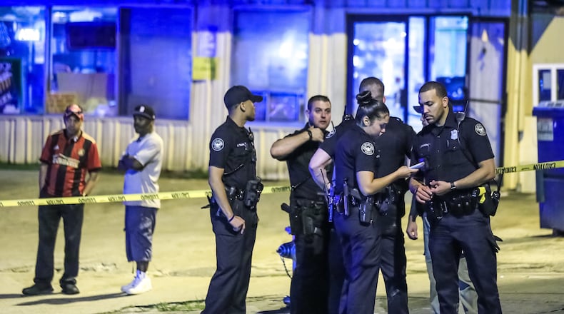 Atlanta police officers investigate a triple shooting at the Quick Pick convenience store near the Greyhound bus station on Forsyth Street.