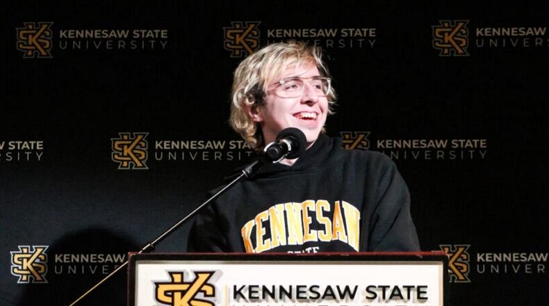 KSU alumnus Raymond Goslow on his “Jeopardy!”: Blonde, white man speaking at podium with KSU BANNER