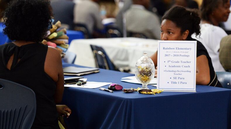 At a DeKalb County Schools job fair last year, a candidate talks with a representative of Rainbow Elementary. Metro Atlanta school districts use a variety of outreach to attract new teachers.