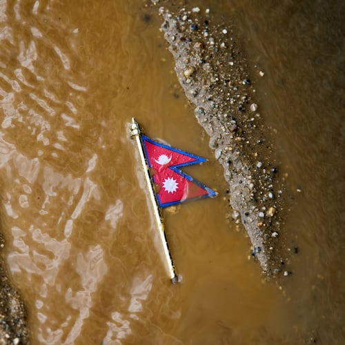 A Nepal flag lies on a muddy track near the banks of the Trishuli river in Dhading District, Nepal, Sunday, Aug. 30, 2026. (AP Photo/Niranjan Shrestha)
