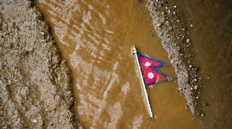 A Nepal flag lies on a muddy track near the banks of the Trishuli river in Dhading District, Nepal, Sunday, Aug. 30, 2026. (AP Photo/Niranjan Shrestha)