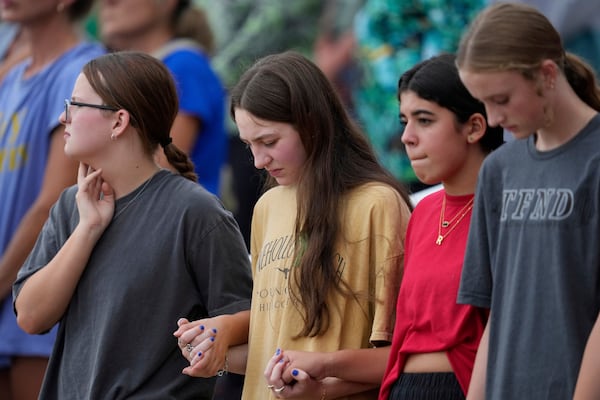 Attendees hold hands during a vigil for flooding victims at Tivy Antler Stadium on Wednesday, July 9, 2025, in Kerrville, Texas. (AP Photo/Ashley Landis)