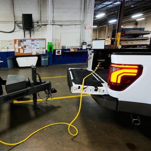A one-foot long adapter is shown connected to a 240-volt outlet onboard a Ford F-150 King Ranch, Wednesday, July 22, 2026, in Southgate, Mich. The adapter makes the vehicle compatible to plug into a longer, separate cable that connects to a transfer switch installed directly on one's electric meter. (AP Photo/Paul Sancya)