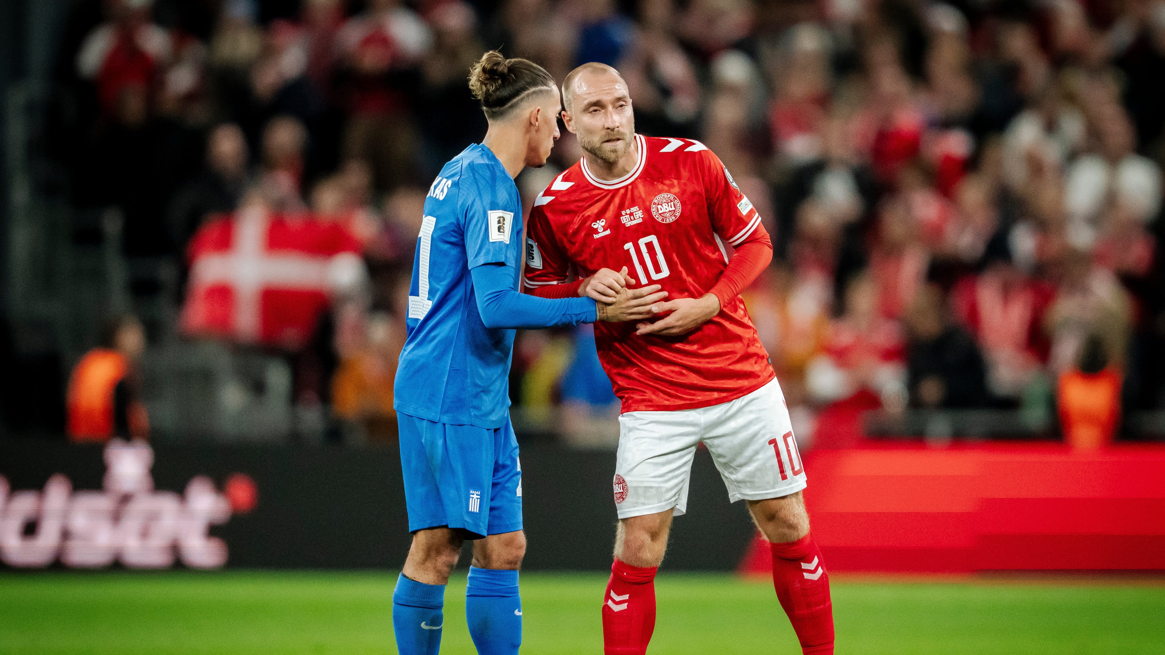 Greece's Kostas Tsimikas, left, and Denmark's Christian Eriksen, right, meet after the World Cup Group C qualification match between Denmark and Greece at Parken stadium in Copenhagen, Sunday, Oct. 12, 2025. (Mads Claus Rasmussen/Ritzau Scanpix via AP)