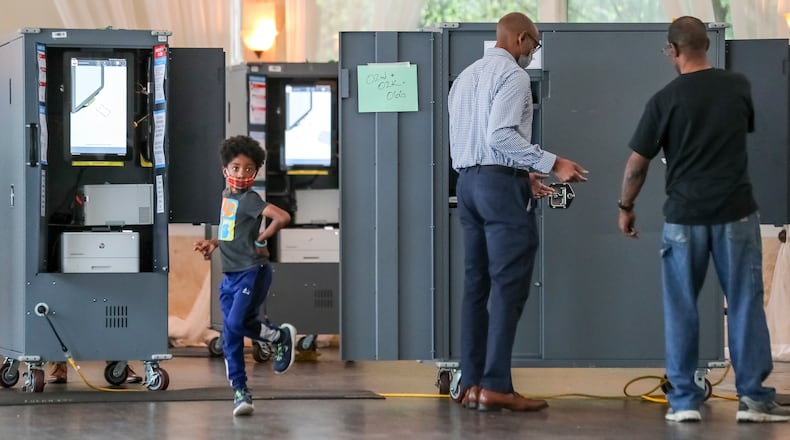 May 25, 2022 Atlanta: Dancing was in while Dad voted (center) at Park Tavern located at 500 10th Street NE, Atlanta. The Father declined to give his name or the name of his son. Voters encountered short lines and limited problems as election day got underway in Georgia on Monday, May 25, 2022 making their voices heard in one of the politically competitive states in the nation. But there were initial hiccups in a few voting locations. Some voters arrived at the polls to find their precincts had been moved to different locations. Others had short waits during the initial morning rush. Several voting locations had problems starting voting machines. In Fulton County, voting was running smoothly at almost all of the county's 250 polling sites, in part thanks to the 91,000 voters who cast their ballots during three weeks of early voting, said Interim Elections Director Nadine Williams. Two polling places, Hopewell Middle in Milton and Creel Park in South Fulton, opened 20 to 30 minutes late. Williams didn't provide a reason for the delays, but she said the county is asking a judge to allow the sites to close later so everyone can vote. She said some poll workers were 'no-shows' but they had staff in reserve. Williams encouraged folks to vote during lunch hours. The New Georgia Project, a voting rights group which monitors election issues, reported the polling place at Bethesda Elementary School in Gwinnett County opened about 30 minutes late. At North Decatur Presbyterian Church, two voting touchscreens weren't working because of a problem with their batteries, but poll workers said they had enough functioning touchscreens to avoid delays. About 70 voters cast ballots in the first hour of voting. Another voter, Marcia King, said she needed help from a poll worker to figure out how to print her ballot from the touchscreen. 'This was very easy with no problems at all, and people were there to help," King said. (John Spink / John.Spink@ajc.com)