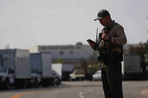 A sheriffs deputy monitors a street closure near the site of an explosion at the LA County Sheriff's Special Operations Bureau on Friday, July 18, 2025, in Los Angeles. (AP Photo/Etienne Laurent)