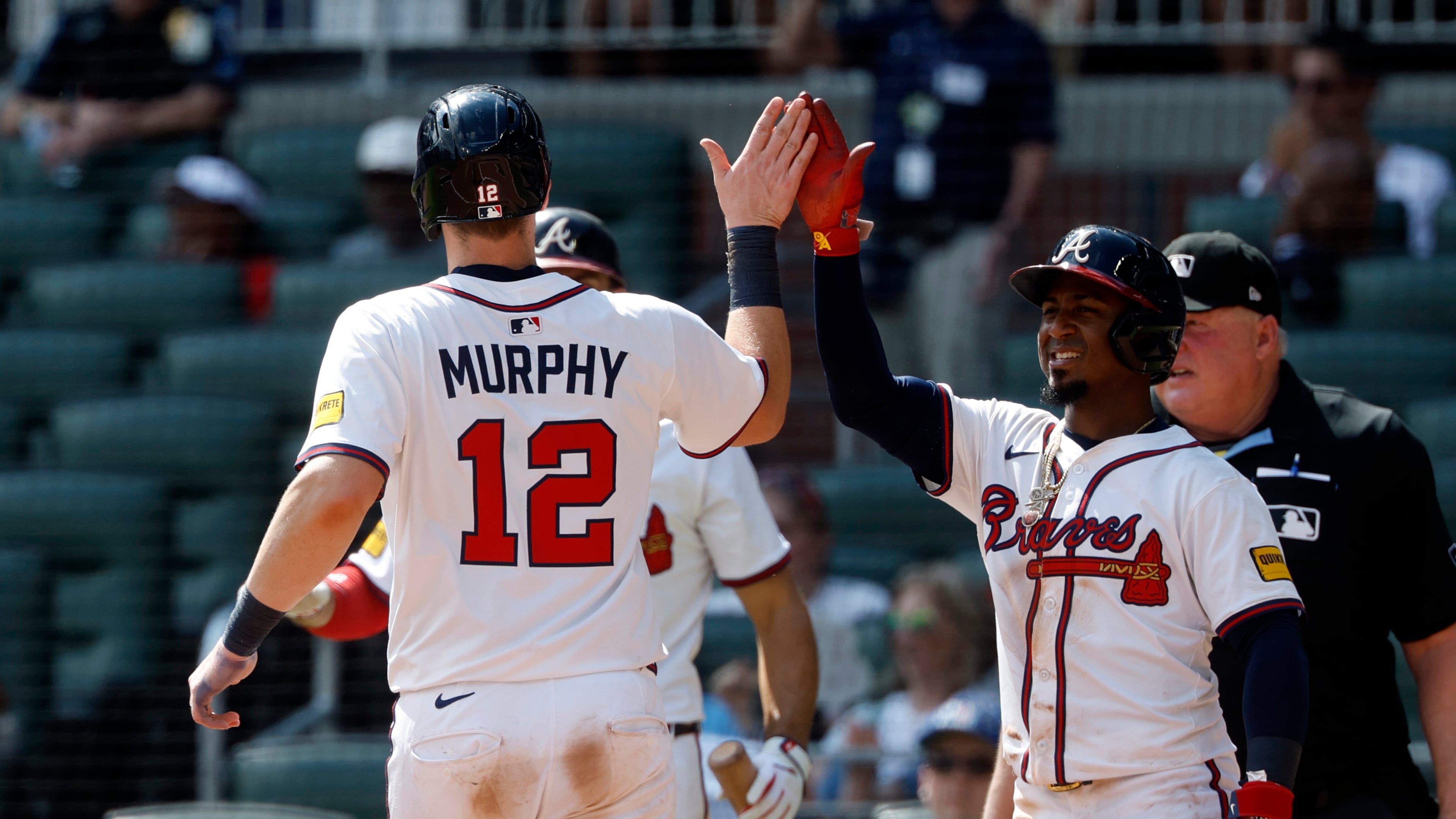 Atlanta Braves' Sean Murphy (12) and Ozzie Albies, right, celebrate after scoring on a hit by Jurickson Profar during the eighth inning of a baseball game against the New York Mets, Sunday, Aug. 24, 2025, in Atlanta. (AP Photo/Butch Dill)
