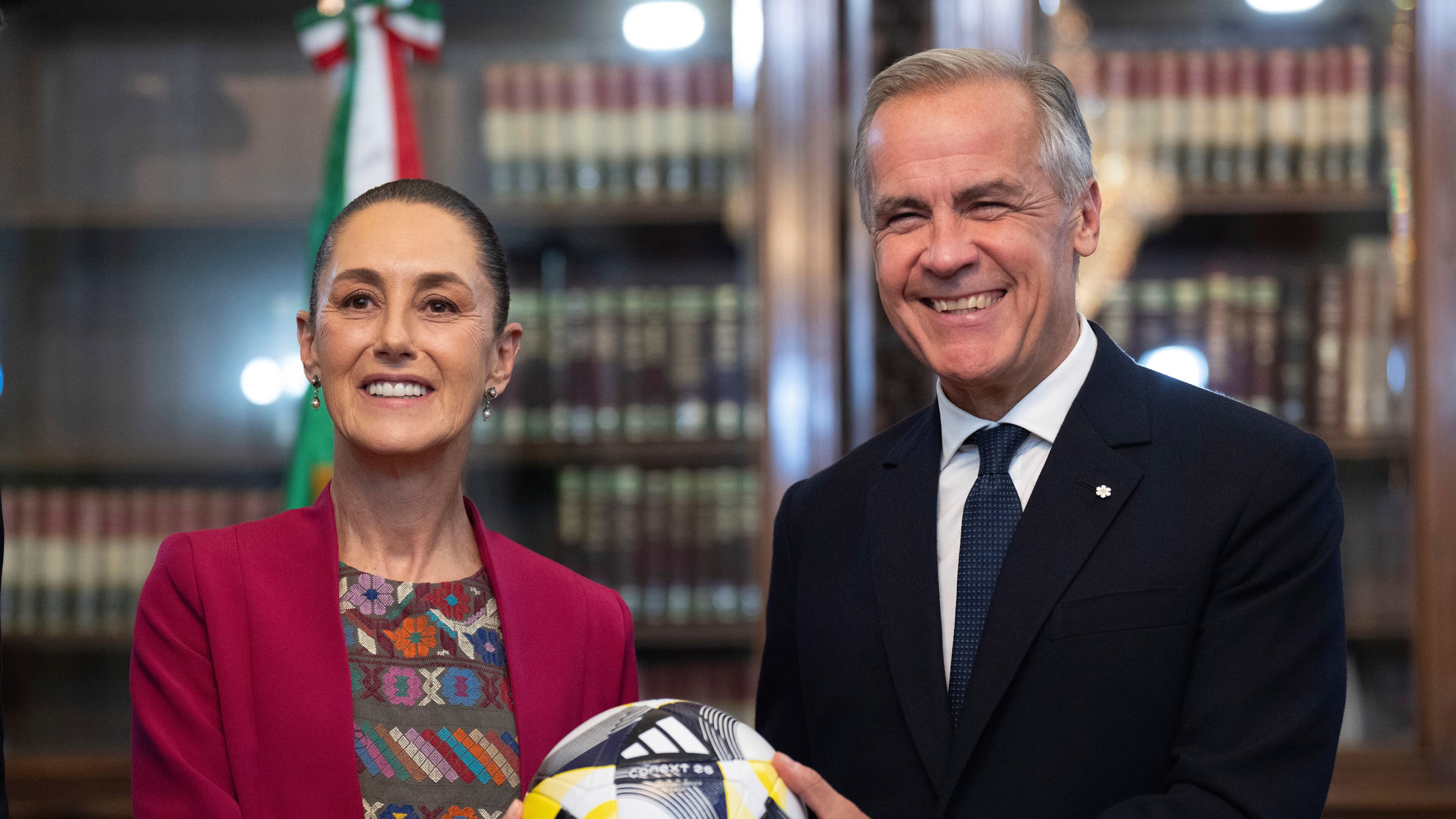 Canada's Prime Minister Mark Carney, right, presents Mexican President Claudia Sheinbaum with an official World Cup soccer ball before they meet at the Palacio National in Mexico City, Thursday, Sep 18, 2025. (Adrian Wyld/The Canadian Press via AP)