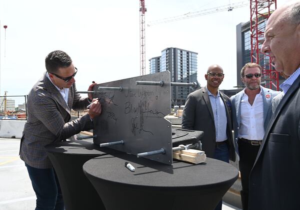 Jeb Terry (left), president and CEO of Cosm, signs on a dome anchor to celebrate during the Cosm Atlanta Steel Rising Ceremony, Thursday, May 15, 2025, in Atlanta. (Hyosub Shin/AJC)