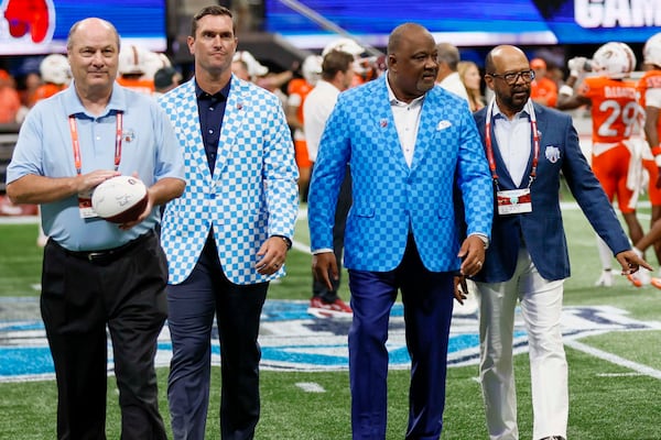 Gary Stokan (from left), Aflac Senior Vice President of Group Voluntary Benefits Bob Ruff, Aflac President Virgil Miller and Peach Bowl Chairman Percy Vaughn walk off the field after the coin toss just before the Aflac Kickoff Game between South Carolina and Virginia Tech at Mercedes-Benz Stadium on Aug. 31. (Miguel Martinez/AJC)
