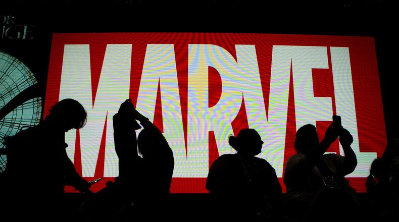 Attendees sit in front of an illuminated Marvel sign during the second day of Comic-Con 2016 in San Diego. This year’s event is July 20-23. Harrison Hill/Los Angeles Times/TNS