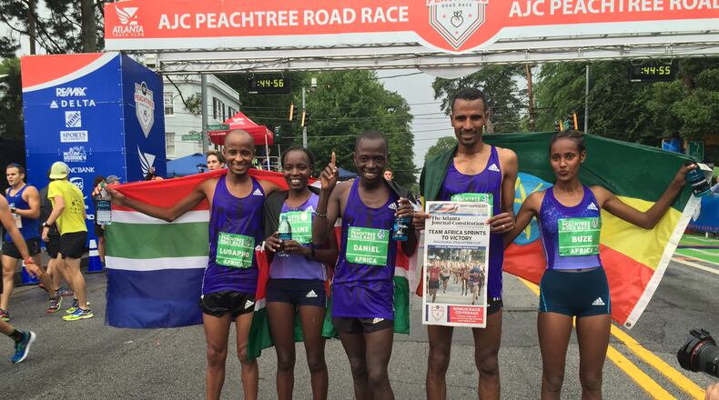 The runners of Team Africa gather with a mock A1 of The Atlanta Journal-Constitution, after completing the 2015 AJC Peachtree Road Race. Team Africa includes: Lusapho April, Buze Diriba, Gebre Gebremariam, Valentine Kibet, Caroline Kilel and Daniel Salel.