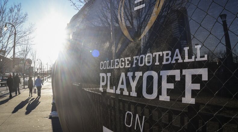 Pedestrians make their way past one of many signs downtown referencing the College Football Playoff National Championship to be held Monday in Atlanta. (John Amis)