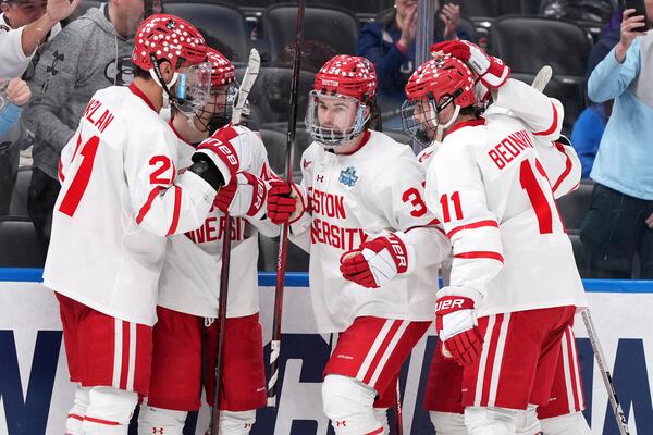 Boston University's Cole Eiserman (34) is congratulated by teammates after scoring during the second period in a semifinal game in the NCAA Frozen Four men's college hockey tournament against Penn State, Thursday, April 10, 2025, in St. Louis (AP Photo/Jeff Roberson)