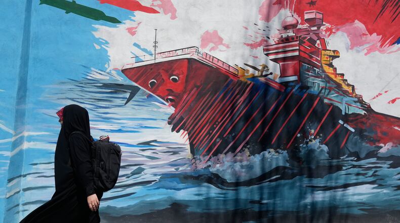A woman walks past a mural depicting a U.S. aircraft carrier under missile attack in downtown Tehran, Iran, Monday, June 8, 2026. (AP Photo/Vahid Salemi)