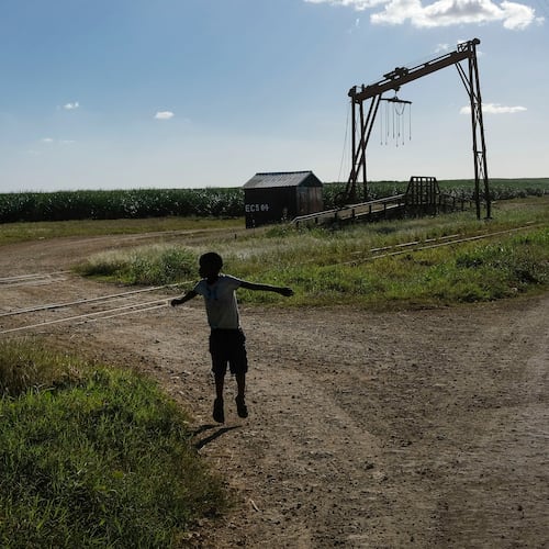 FILE - A youth plays near the machine where the sugar cane is weighed in the Lima batey, or neighborhood, in La Romana, where Central Romana Corporation, Ltd. operates its sugar operations in Dominican Republic, Nov. 17, 2021. (AP Photo/Matias Delacroix, File)