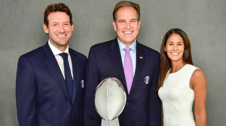 CBS' lead NFL broadcast team of (l-r) Tony Romo, Jim Nantz and Tracy Wolfson stand behind the Lombardi Trophy, presented each year to the Super Bowl winner.