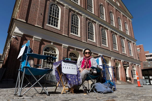 FILE - A fortune teller going by the name of Andrea waits for customers in front of Faneuil Hall in Boston, on a plaza that is usually busy with tourists, March, 14, 2020. (AP Photo/Michael Dwyer, File)