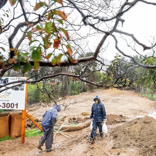 James Jones carries sandbags while trying to prevent water from running off a property scorched in the Eaton Fire in Altadena, Calif., as the region remains under flash flood warnings on Saturday, Nov. 15, 2025. (AP Photo/Noah Berger)