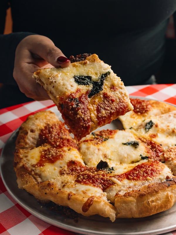 Cheesy garlic bread in the shape of a pizza, with a hand lifting a piece