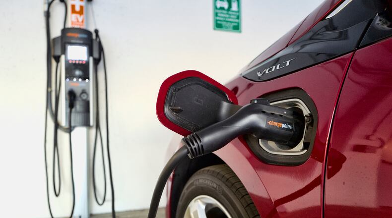 FILE - This Wednesday, Oct. 17, 2018 file photo shows a Chevrolet Volt hybrid car charging at a ChargePoint charging station at a parking garage in Los Angeles. If U.S. consumers ever ditch fuel burners for electric vehicles, then the United Auto Workers union is in trouble. Gone would be thousands of jobs at engine and transmission plants across the industrial Midwest, replaced by smaller workforces at squeaky-clean mostly automated factories that mix up chemicals to make batteries. (AP Photo/Richard Vogel, File)