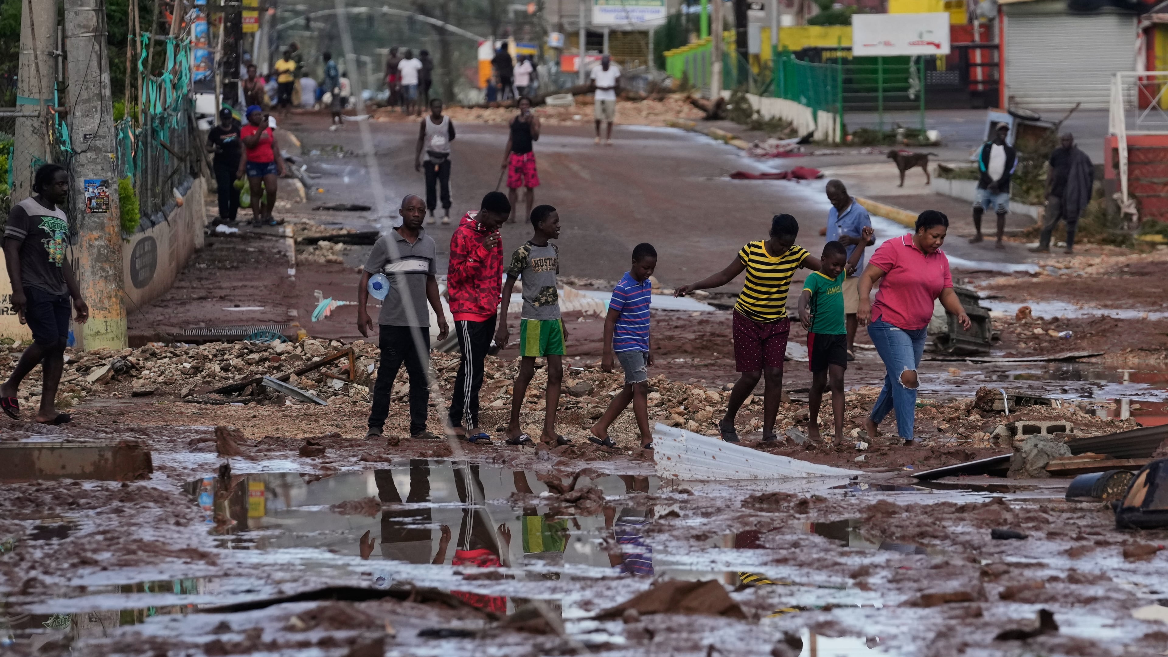 People walk through Santa Cruz, Jamaica, Wednesday, Oct. 29, 2025, after Hurricane Melissa passed. (AP Photo/Matias Delacroix),