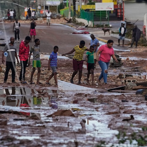 People walk through Santa Cruz, Jamaica, Wednesday, Oct. 29, 2025, after Hurricane Melissa passed. (AP Photo/Matias Delacroix),
