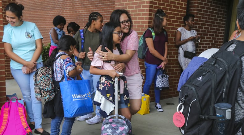 Myrna Gacusan gives 11-year old Rinna a hug before she begins her school day at Coleman Middle School in Duluth on August 7, 2017. The 1996 Summer Olympics in Atlanta triggered a population boom — and international immigrants — in the Atlanta area. With a school system that was already beginning to be considered among the best in the Southeast, Gwinnett County was a popular destination. JOHN SPINK/JSPINK@AJC.COM