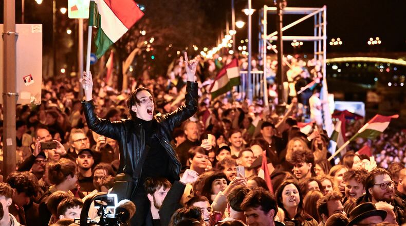 A man waves a Hungarian flag as he celebrates in the streets after the announcement of partial results of the Hungarian parliamentary election in Budapest, Hungary, Sunday, April 12, 2026. (AP Photo/Denes Erdos)
