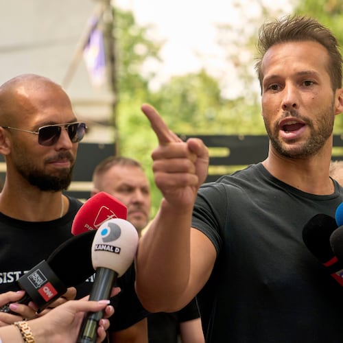 FILE - Andrew Tate, left, watches his brother Tristan speak, outside a police station in Voluntari, Romania, May 21, 2025. (AP Photo/Vadim Ghirda, File)