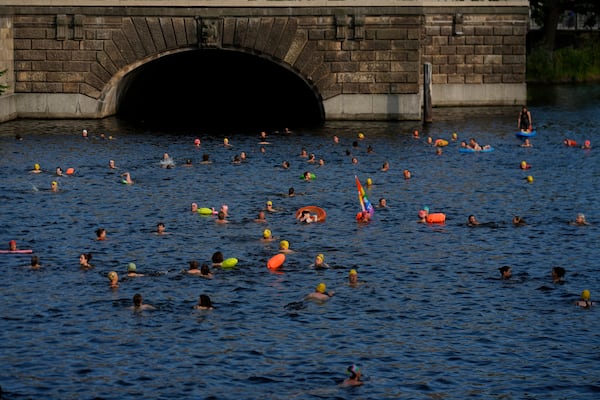 People swim in the river Spree to demand the lift of the hundred years old swimming ban at the river in Berlin, Germany, Tuesday, June 17, 2025. (AP Photo/Markus Schreiber)