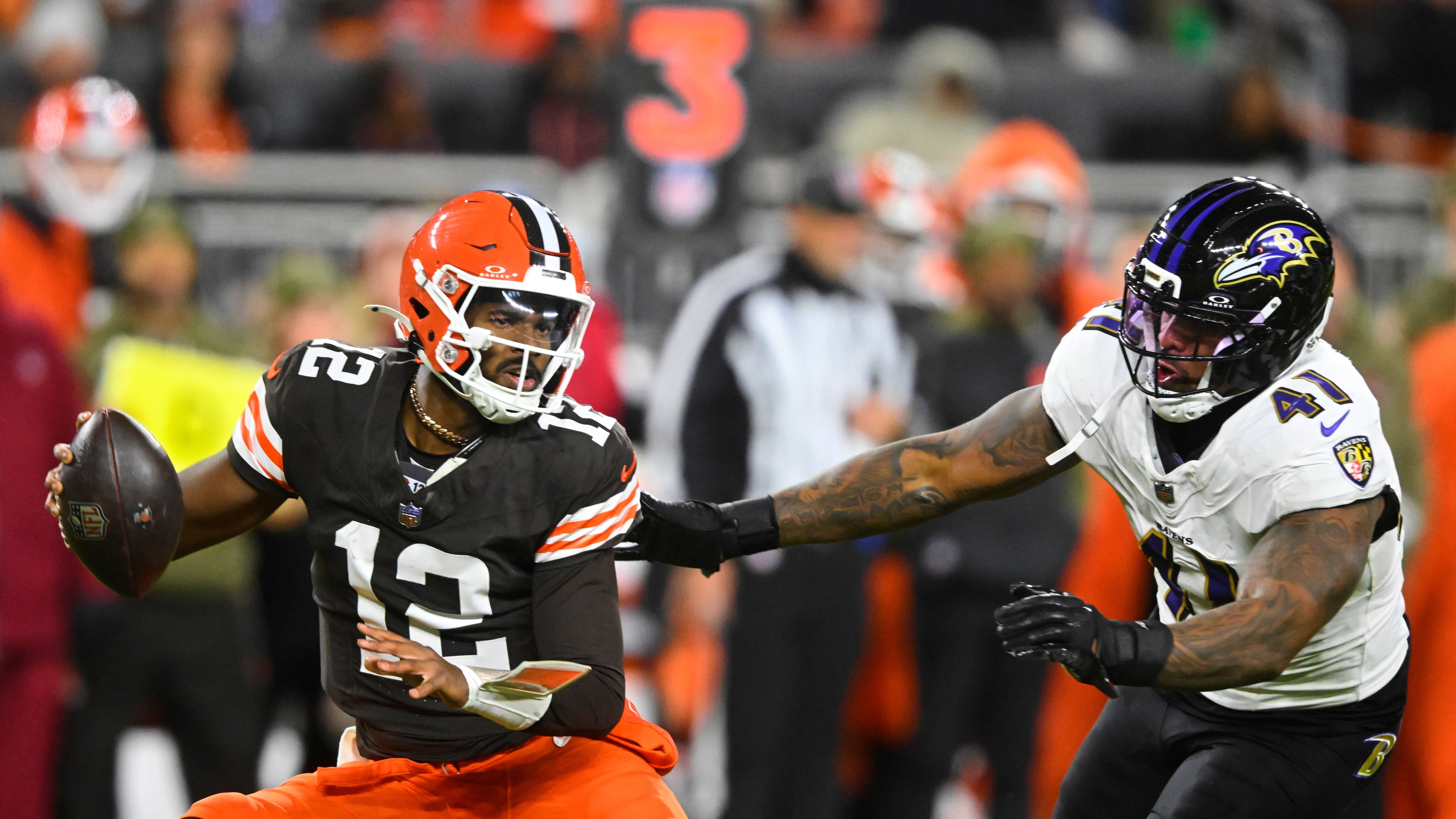 Cleveland Browns quarterback Shedeur Sanders (12) is pressured out of the pocket by Baltimore Ravens' Dre'Mont Jones (41) in the second half of an NFL football game in Cleveland, Sunday, Nov. 16, 2025. (AP Photo/David Richard)