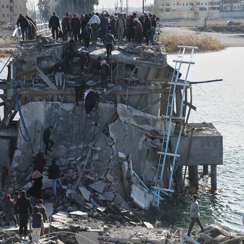 People climb over the damaged Al-Rashid Bridge, with some crossing on foot, after it was destroyed as Kurdish-led Syrian Democratic Forces withdrew, a day after Syrian government forces took control of the area on the outskirts of Raqqa, northeastern Syria, Monday, Jan. 19, 2026. (AP Photo/Ghaith Alsayed)