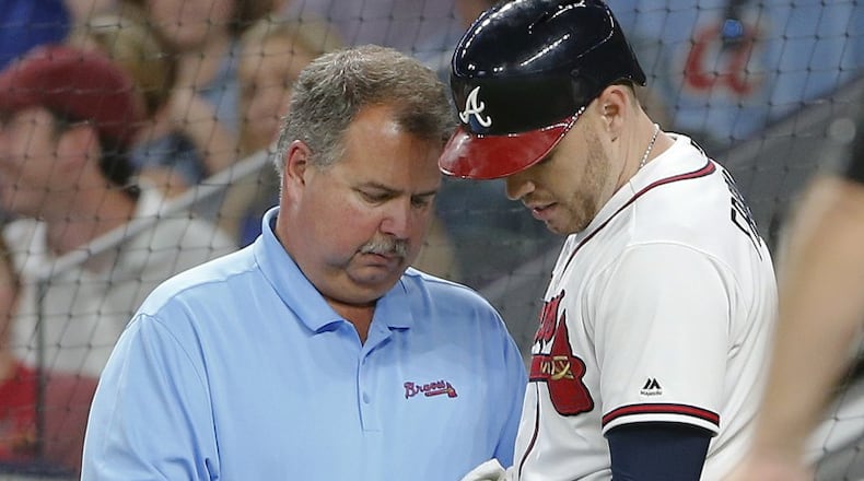 Freddie Freeman is examined after being hit by a pitch in the fifth inning of Wednesday’s game at SunTrust Park. (John Bazemore/AP photo)