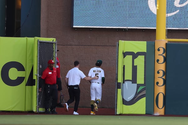 The Athletics trainer, left, and Athletics' Jacob Wilson (5) head to the clubhouse during the first inning of a baseball game against the Atlanta Braves, Tuesday, July 8, 2025, in West Sacramento, Calif. (AP Photo/Scott Marshall)