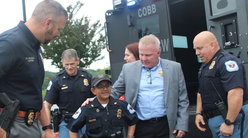 Arya Patel arrives at the Cobb County Police Training Center in a Cobb Police Department BearCat SWAT vehicle with his parents and Cobb officers for his swearing-in as a Cobb Police officer and Cobb firefighter for the day on Friday. Patel, who has osteosarcoma, wished to be a police officer for the day, and Make-A-Wish Georgia partnered with Cobb to make that wish come true.