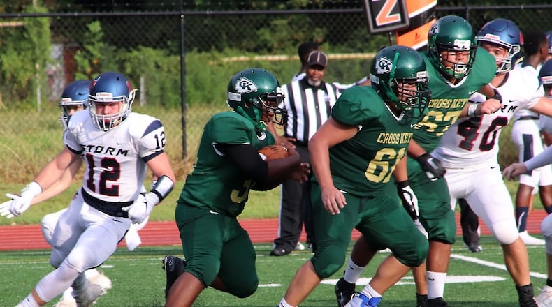 Cross Keys running back Roy Huff (center) looks for yardage behind the blocking of Bryan Guerrero (61) in the Indians' season-opening game against Providence Christian on Aug. 23, 2019, at Adams Stadium in Atlanta.