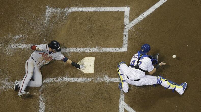 Dansby Swanson slides to score a run Friday in the Braves’ 10-8 win at Milwaukee. He had two walks and scored after each in that game, then had two hits including a home run Saturday. (AP photo)