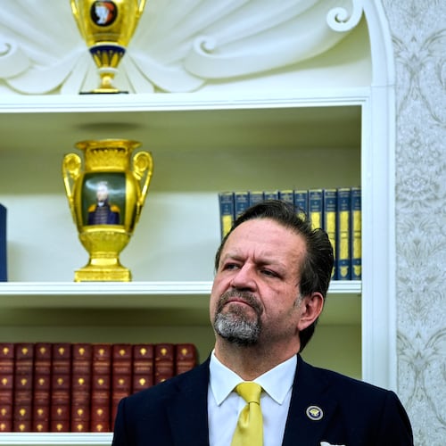 FILE - Sebastian Gorka listens as President Donald Trump speaks with reporters after signing executive orders in the Oval Office of the White House, April 23, 2025, in Washington. (AP Photo/Alex Brandon, File)