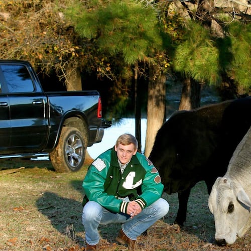 Georgia Tech quarterback Haynes King poses with his father's bull Gunsmoke on the family's 12-acre farm. King grew up tending to the family's cattle. As John King told it, the black cow in the background was not supposed to be in the photo but wouldn't get out of the frame. (Courtesy of John King)