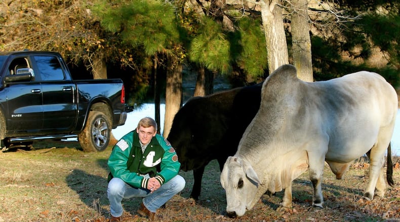 Georgia Tech quarterback Haynes King poses with his father's bull Gunsmoke on the family's 12-acre farm. King grew up tending to the family's cattle. As John King told it, the black cow in the background was not supposed to be in the photo but wouldn't get out of the frame. (Courtesy of John King)